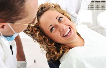 Happy woman in a dental chair after dental bonding procedure.