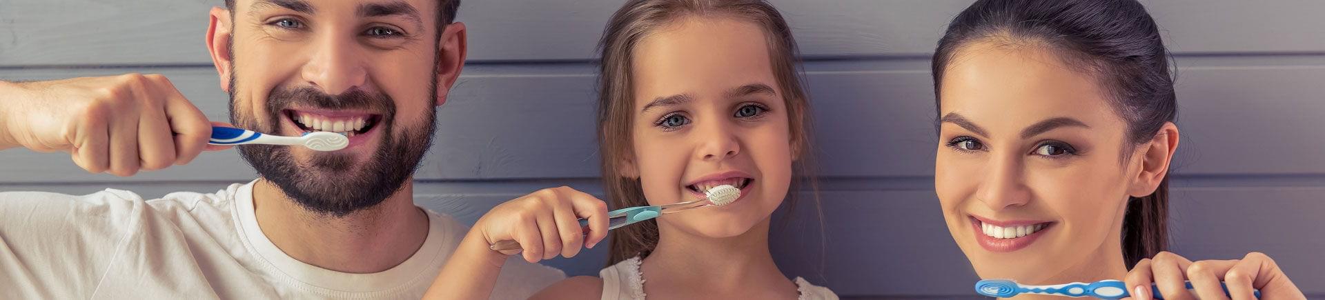 Parent and their little daughter having fun brushing their teeth.