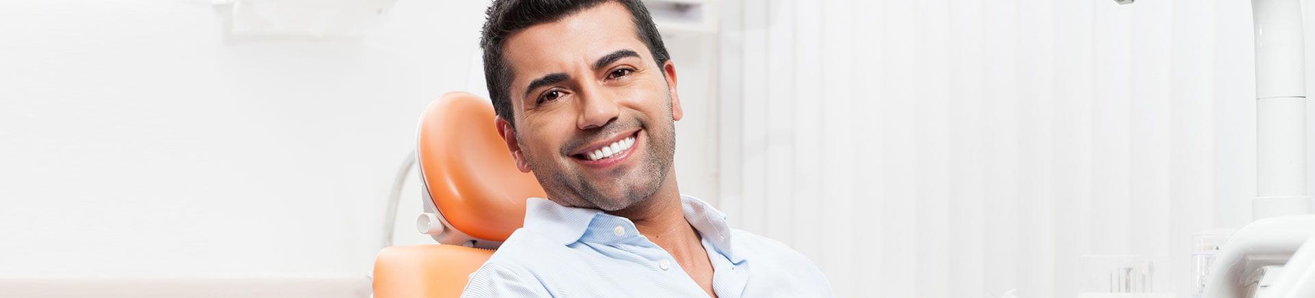 A satisfied middle-aged man with a perfect smile sitting in a dental chair.