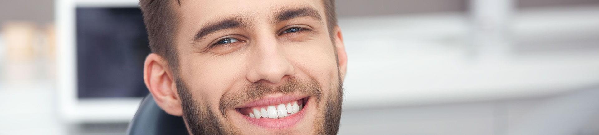 A happy young man in a dental chair showing beautiful teeth in his smile.