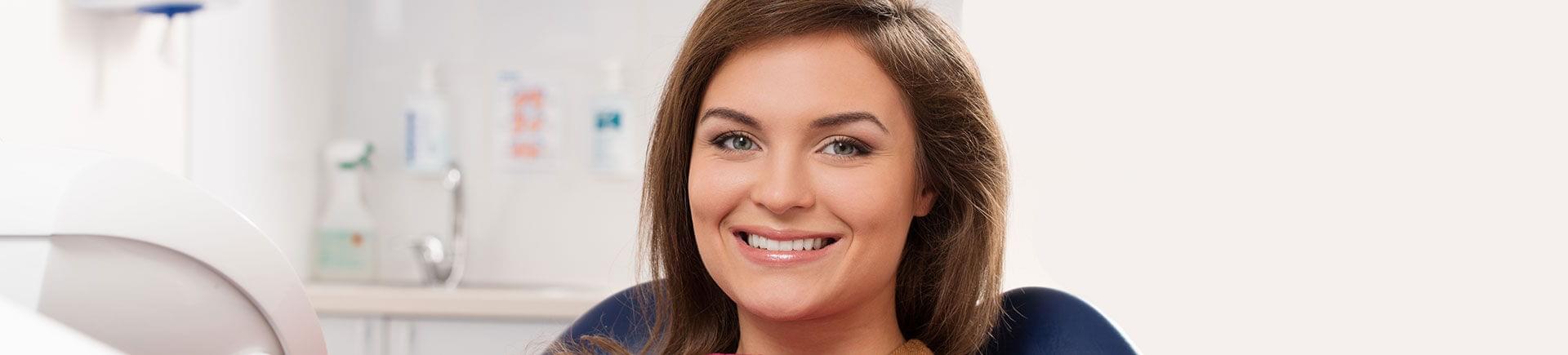 A cheerful young woman with a perfect smile at a dental appointment.