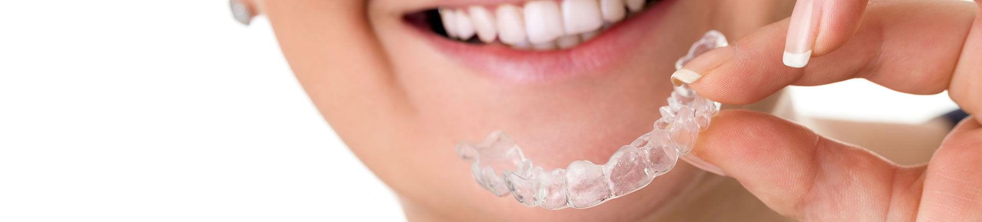 A woman holding an Invisalign aligner .