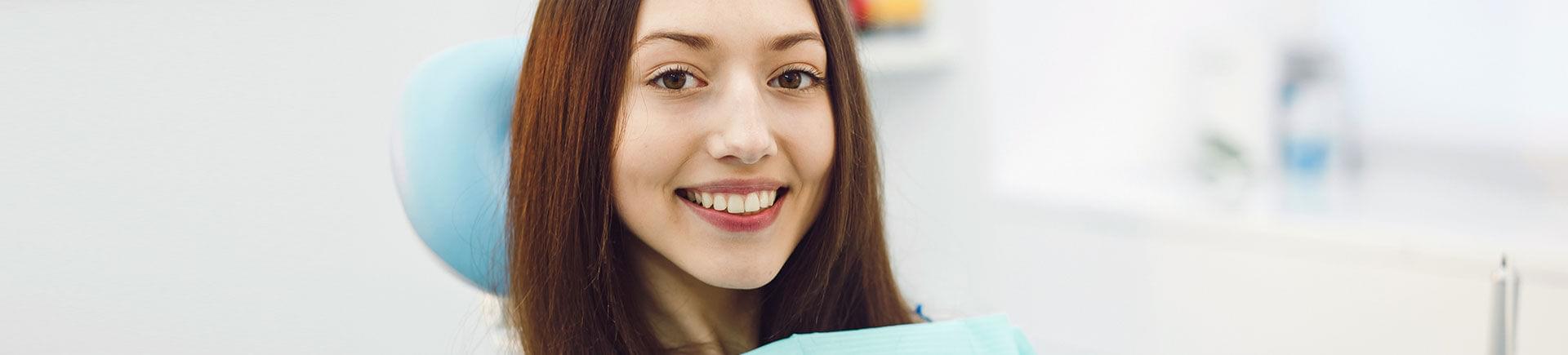 Relaxed smiling young woman in a dental chair after tooth extraction procedure.