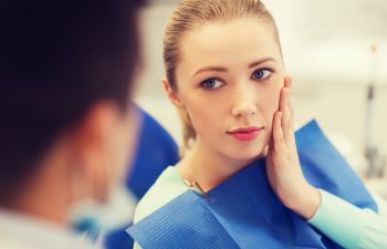 A woman with dental pain during a dental appointment.