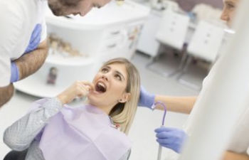 A young woman during a dental appointment showing the problem area to the dentist.