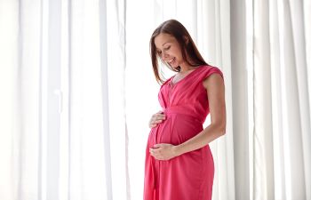 Happy pregnant woman touching her belly.