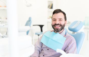 Smiling satisfied man sitting in a dental chair at a dental clinic.
