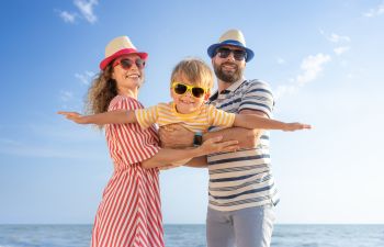 Happy parents playing with their little son on a beach.