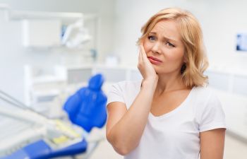 A woman suffering from dental pain in a dentist office.